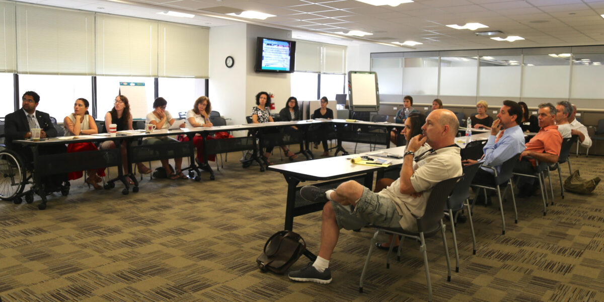 A group of individuals meet in a conference room of the New York Department of Transportation.